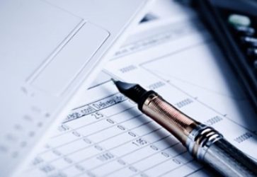 Caneta calculadora e papeis na mesa prontos para fazer a declaração de imposto de renda