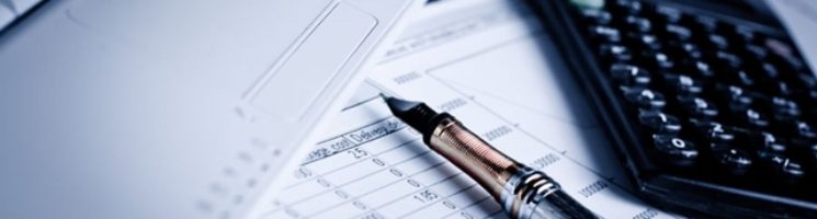 Caneta calculadora e papeis na mesa prontos para fazer a declaração de imposto de renda
