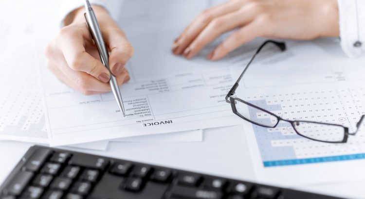 Diferenças entre NFE e NFCE - Pessoa assinando documentos e notas fiscais - Penta Certificação Digital